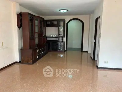 Spacious living room with elegant wooden furniture and glossy tiled floor.