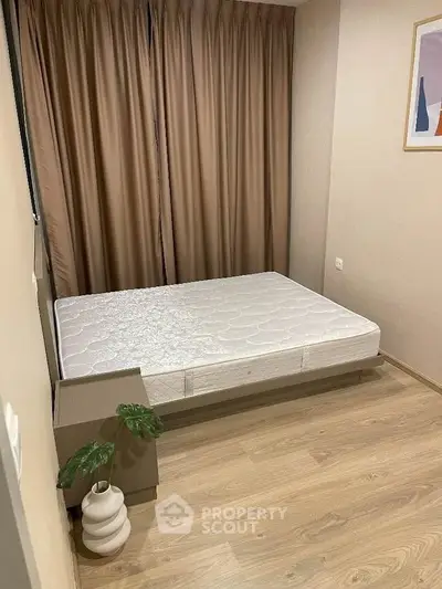 Cozy minimalist bedroom with wooden flooring and elegant curtains.