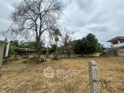 Spacious vacant land with potential for development, surrounded by lush greenery and residential homes.