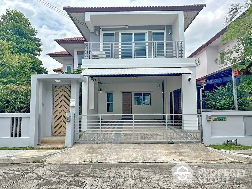 Modern two-story house with gated entrance and driveway in a suburban neighborhood.