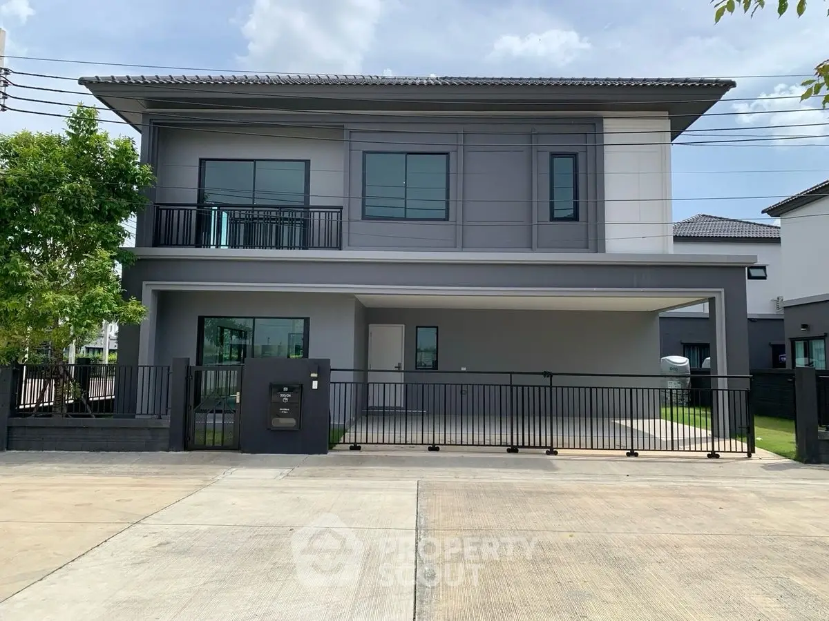 Modern two-story house with sleek design and spacious driveway in suburban neighborhood.