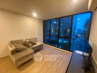 Modern living room with large windows and cozy seating in urban apartment