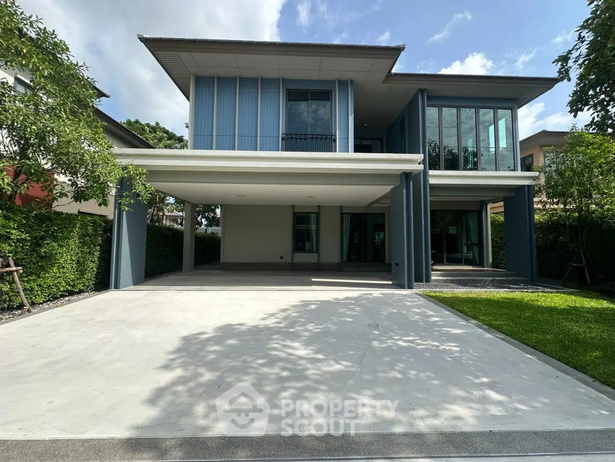 Modern two-story house with spacious driveway and lush greenery