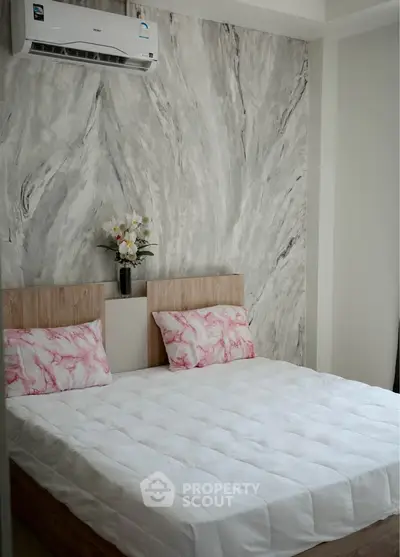 Cozy bedroom with modern decor and air conditioning, featuring a stylish accent wall and comfortable bedding.