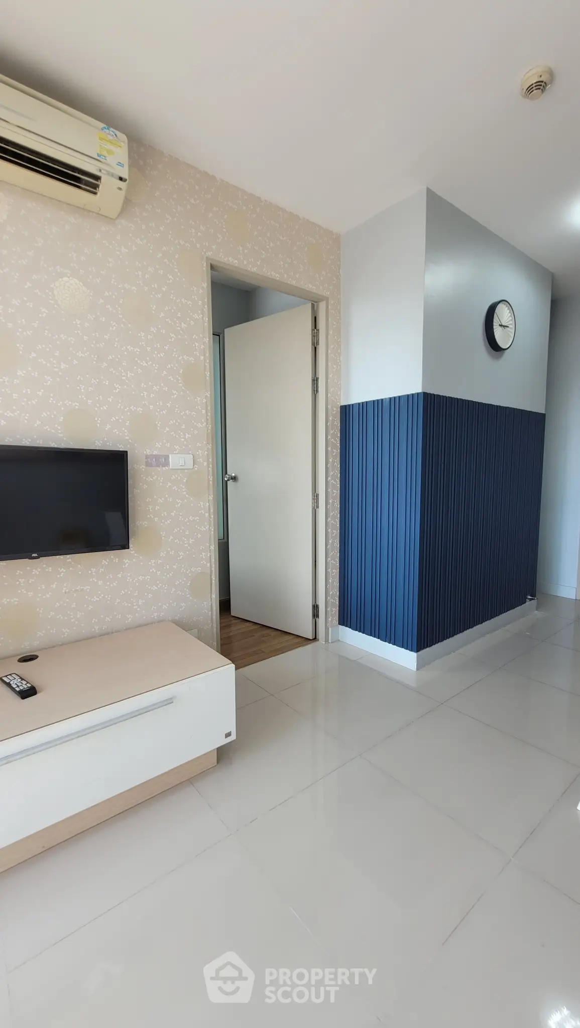 Modern living room with sleek design and wall-mounted TV, featuring stylish blue accent wall and air conditioning.