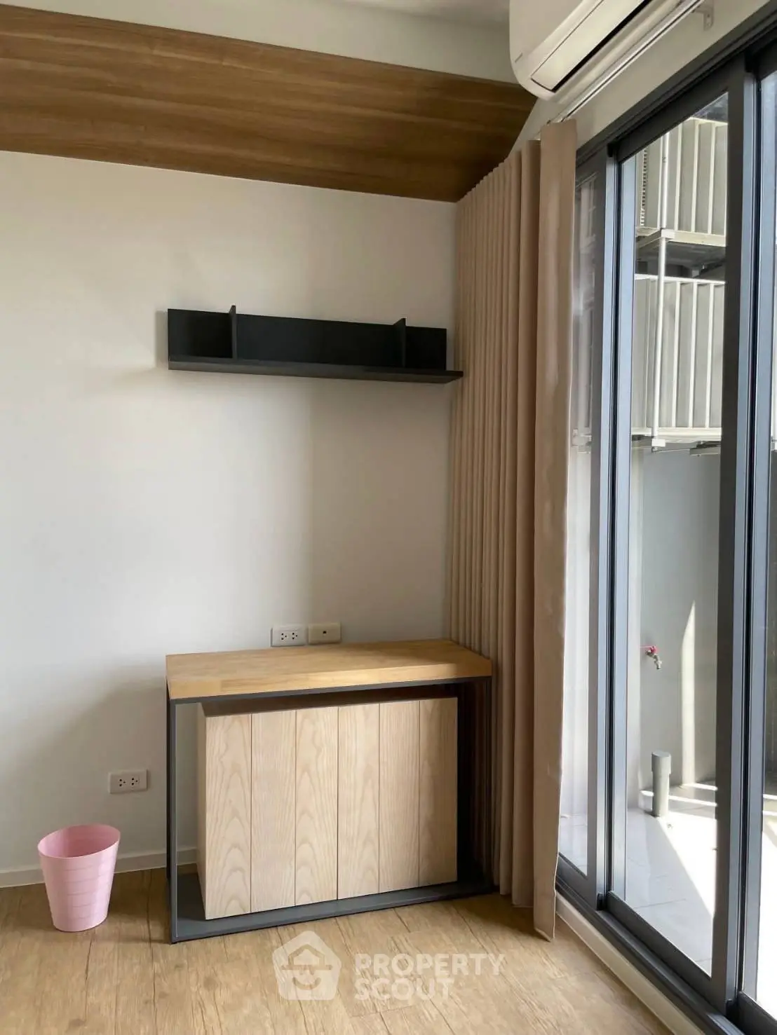 Modern study nook with wooden desk and shelf near large window in stylish apartment.