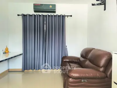 Cozy living room with leather sofa and modern air conditioning unit, perfect for relaxation.