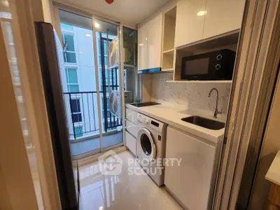 Modern kitchen with sleek appliances and balcony view in a high-rise apartment.