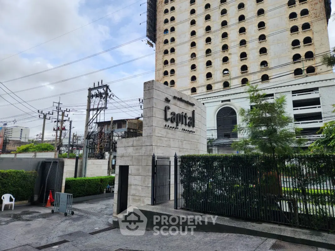 Modern high-rise building exterior with lush greenery and secure gated entrance.