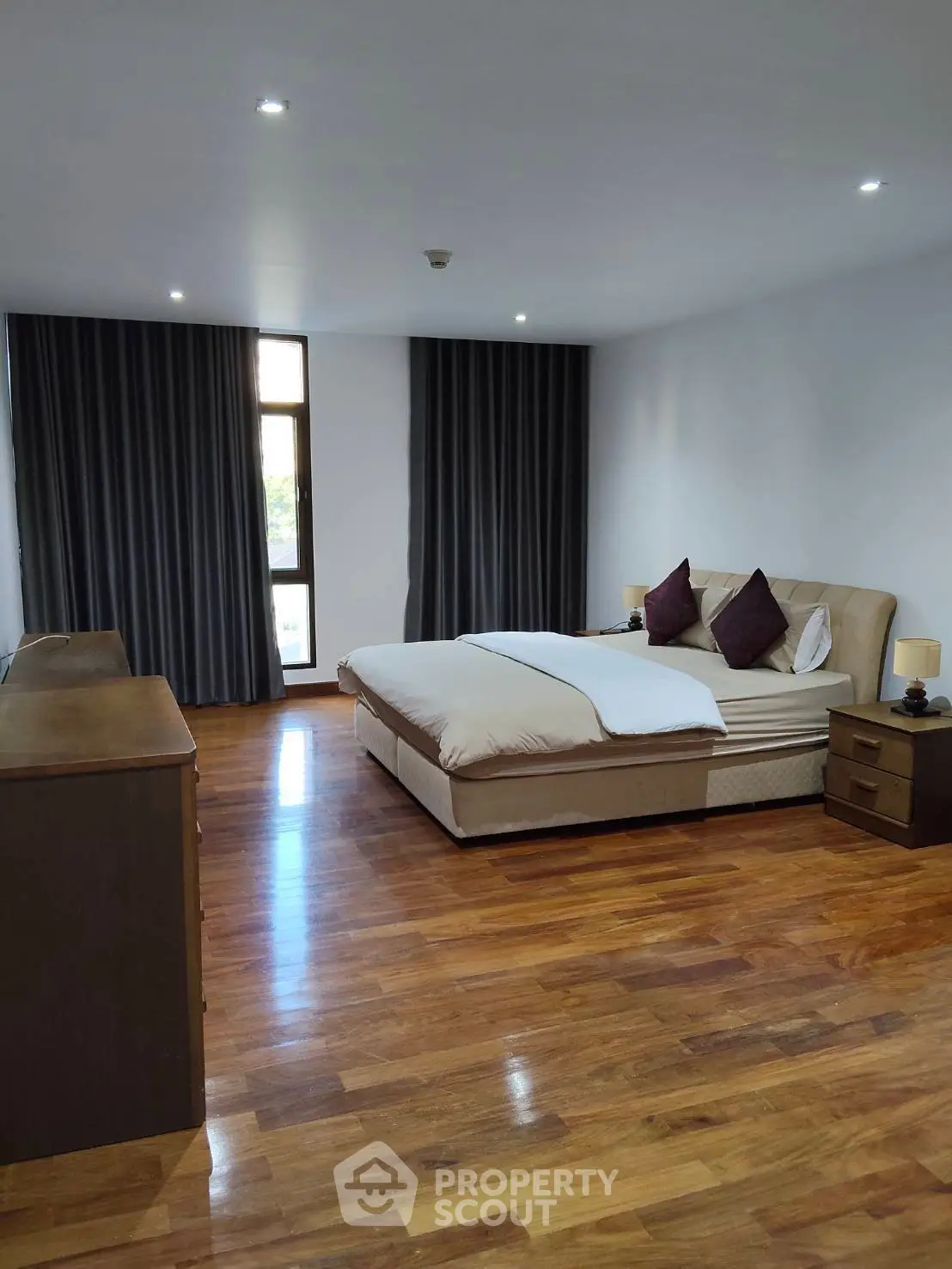 Spacious bedroom with elegant wooden flooring and modern decor in a luxury apartment.
