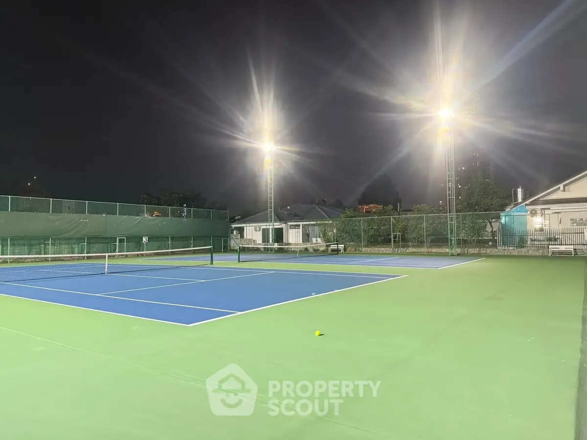 Illuminated outdoor tennis court at night in a residential complex