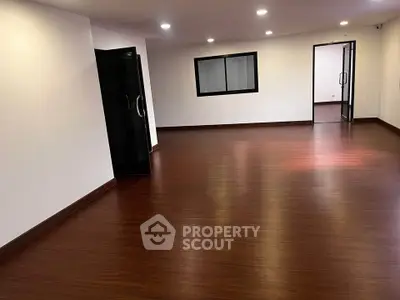 Spacious empty room with wooden flooring and modern lighting, ideal for customization.