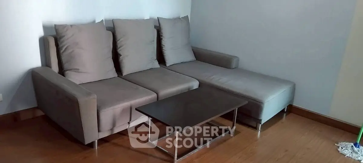 Modern living room with sleek gray sofa and minimalist coffee table on wooden floor.
