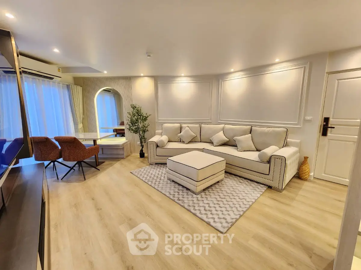 Elegant living room with modern decor, featuring a plush sofa, stylish chairs, and ambient lighting.