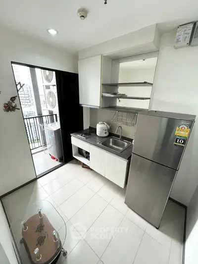 Modern compact kitchen with balcony access in urban apartment