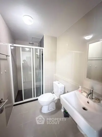Modern bathroom with shower, toilet, and sink in a sleek, minimalist design.