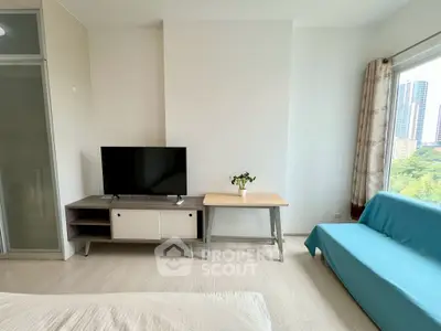 Modern living room with TV, stylish furniture, and large window with city view.