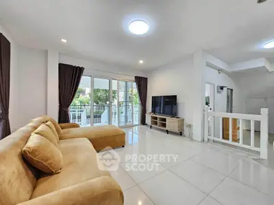 Spacious living room with modern decor and large windows opening to a balcony.