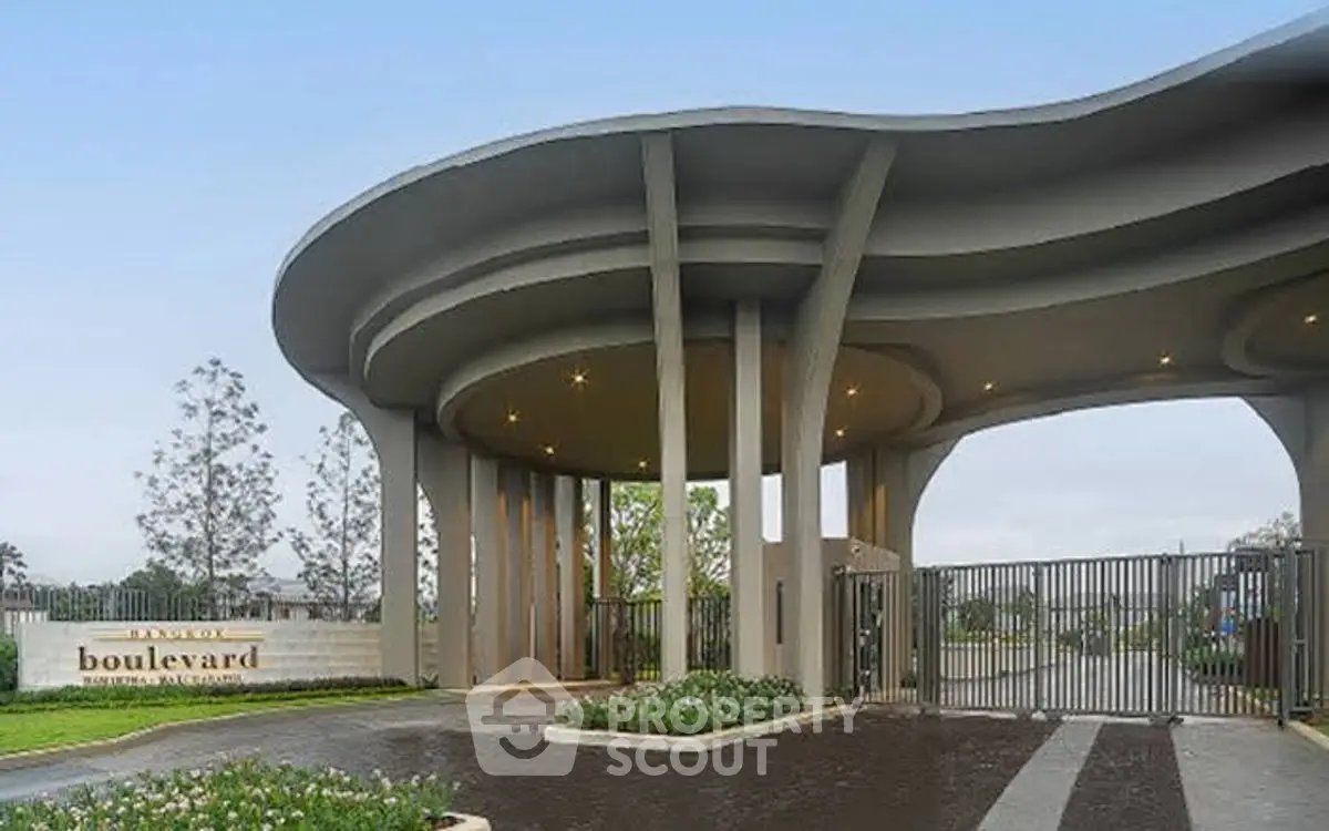 Luxurious gated entrance of modern residential complex with elegant architectural design.