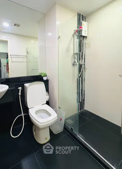 Modern bathroom with glass shower and sleek black flooring