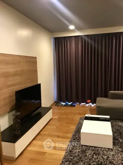 Cozy living room with warm wooden flooring, modern furniture, and elegant dark curtains, perfect for relaxation and entertainment.