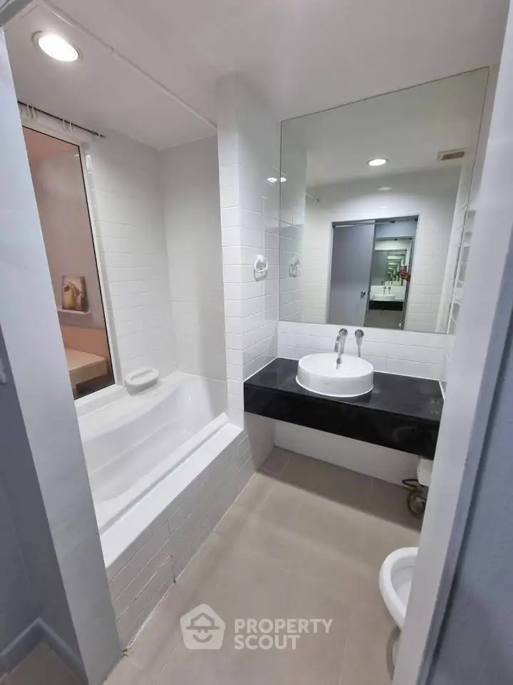 Modern bathroom with sleek design featuring a bathtub and stylish sink area.