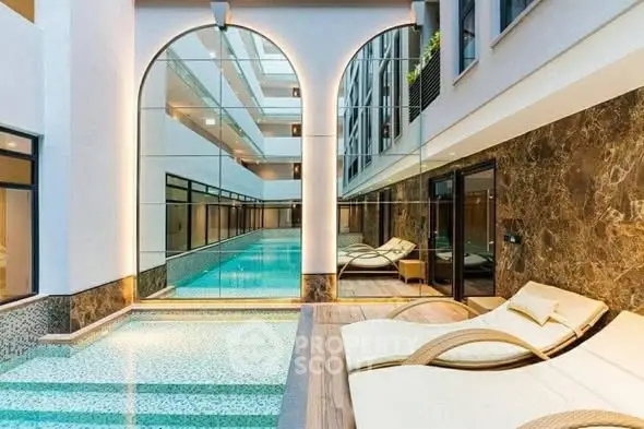 Luxurious indoor pool area with elegant lounge chairs and modern design.