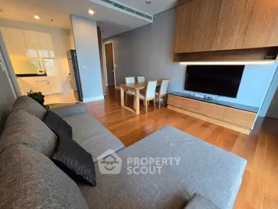 Spacious modern living room with open kitchen and dining area, featuring sleek furniture and wooden flooring.
