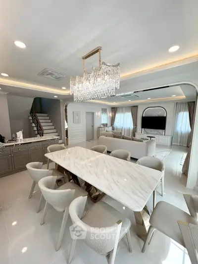 Luxurious open-plan living and dining area with elegant chandelier and marble table.