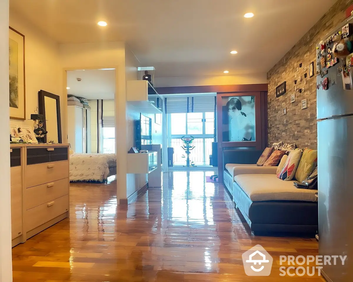 Spacious living room with polished hardwood floors, modern furnishings, and abundant natural light from large windows, perfect for urban living.