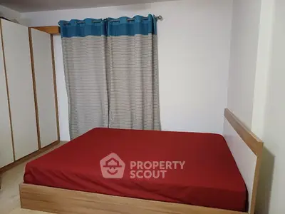 Cozy bedroom with red bedding and stylish curtains, perfect for a restful retreat.