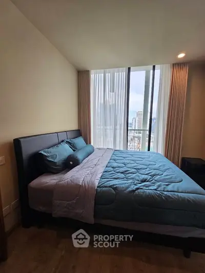 Modern bedroom with city view, featuring a cozy bed and large window for natural light.