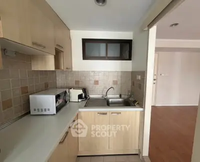 Modern kitchen with wooden cabinets and stainless steel sink in a cozy apartment.