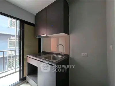 Modern compact kitchen with sleek cabinetry and balcony view