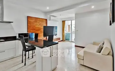 Modern open-layout living room with kitchen and balcony access, featuring sleek furniture and natural light.