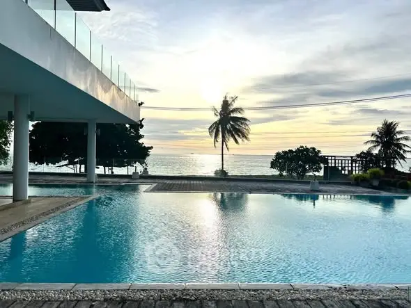 Stunning beachfront pool with ocean view and palm trees at sunset.