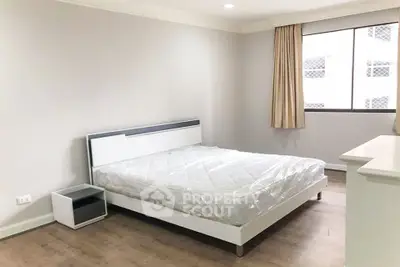 Spacious bedroom with modern bed and natural light in a stylish apartment.