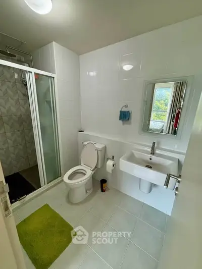 Modern bathroom with shower and sleek fixtures in a bright, tiled space.