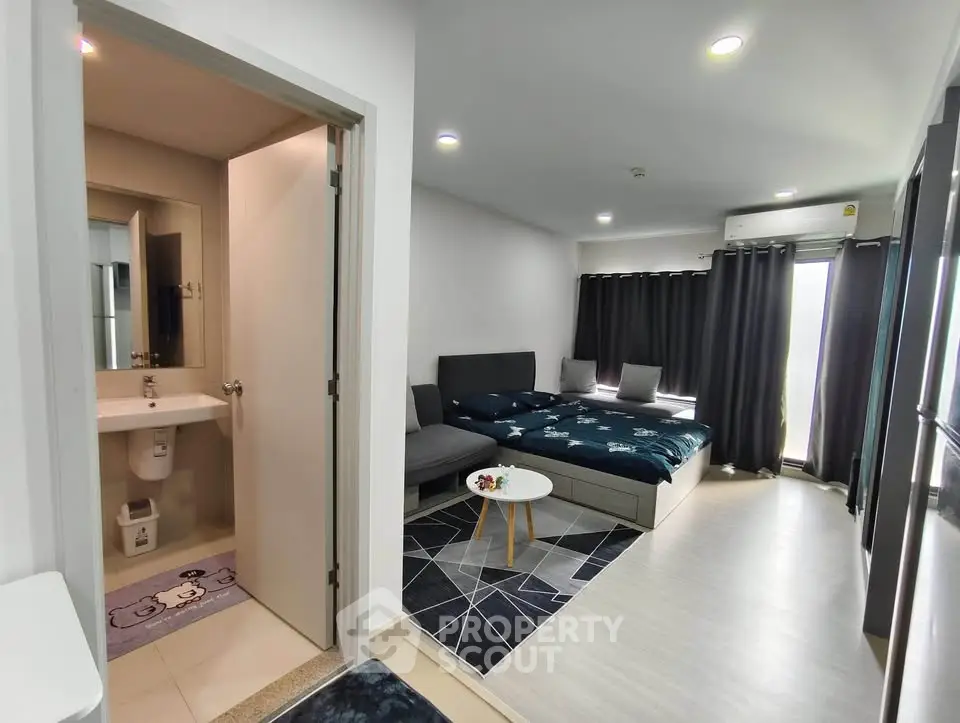 Modern studio apartment with cozy living area and bedroom, featuring sleek design and ample natural light.