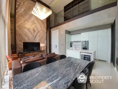 Luxurious open-concept living space with high ceilings, marble dining table, modern kitchen, and elegant chandelier, perfect for entertaining.