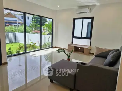 Spacious modern living room with large windows and garden view, perfect for relaxation and natural light.