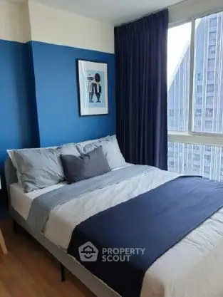 Modern bedroom with blue accent wall and city view, perfect for urban living.
