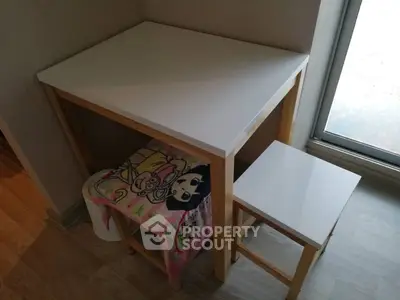 Cozy corner with a small white table and stool, perfect for a compact study or reading nook.