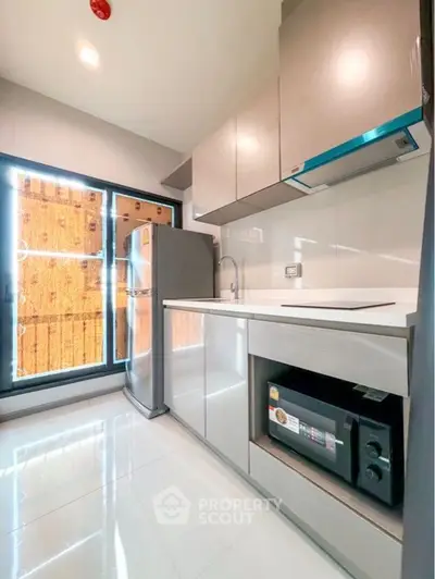 Modern kitchen with sleek cabinets and stainless steel appliances in a bright, compact space.