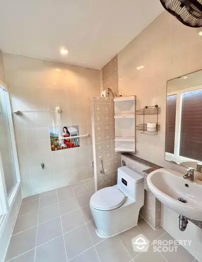 Modern bathroom with sleek fixtures and neutral tiles, featuring a spacious shower area.