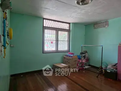 Spacious room with wooden flooring and large window, ideal for storage or creative use.