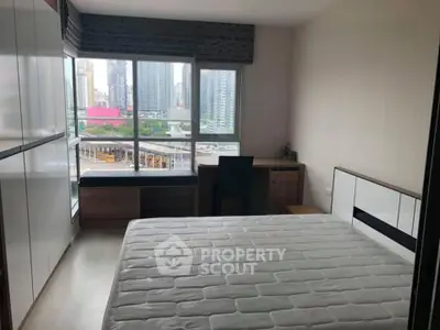 Modern bedroom with city view, featuring large windows and sleek furniture design.