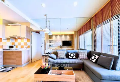 Modern living room with open kitchen, stylish decor, and ample natural light.