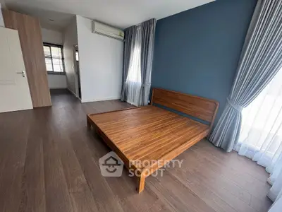 Spacious bedroom with wooden flooring and modern design in a stylish apartment.