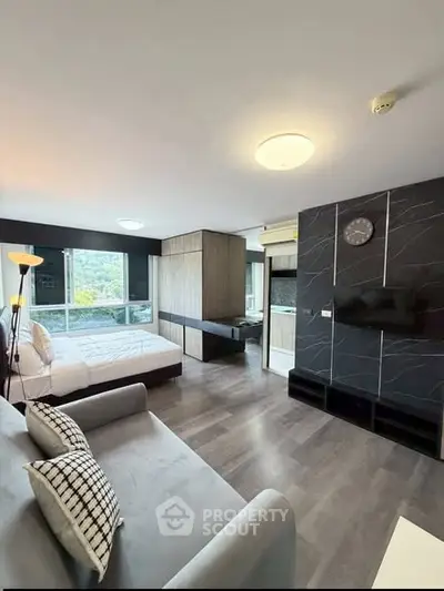 Modern studio apartment with stylish decor and large windows offering natural light.